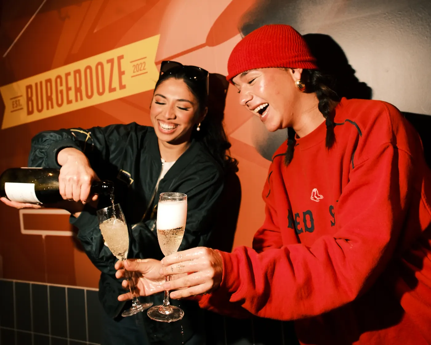 Guests raising a glass in front of the Burgerooze wall