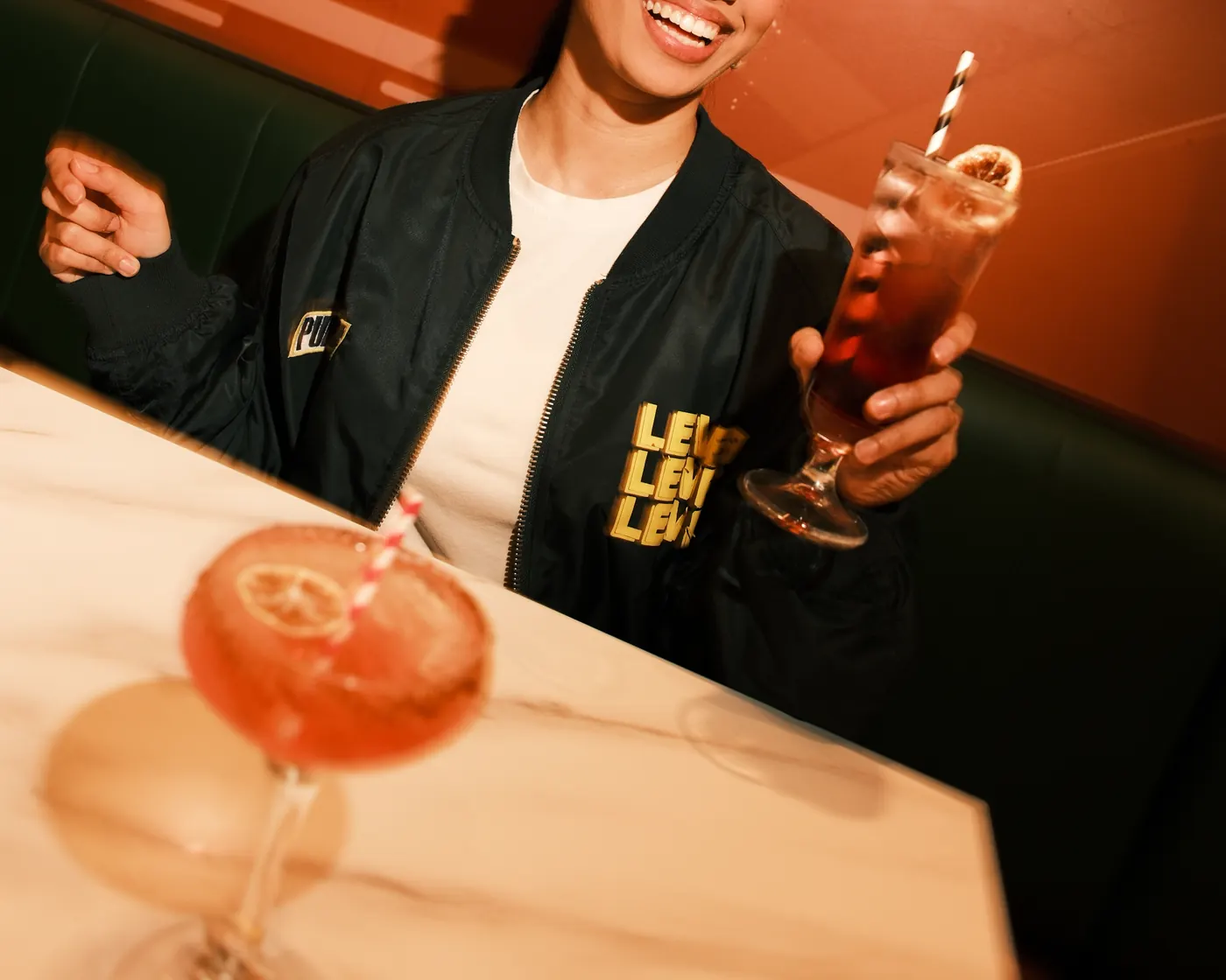 A guest seated with a drink in the booth